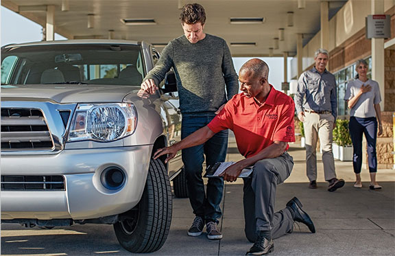 Service Tech touching tire, three people near service tech